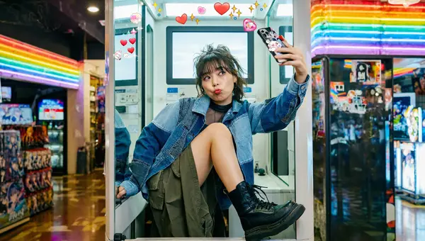 Z Image hyper-realistic output — young Japanese woman taking a selfie in a purikura photo booth with neon arcade backdrop and authentic lighting